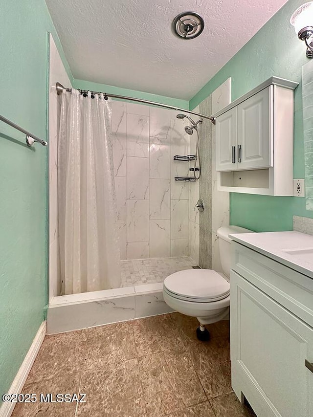 bathroom with a textured wall, toilet, vanity, a shower stall, and a textured ceiling