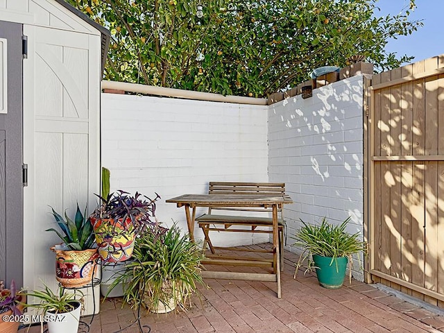 view of patio / terrace with fence and an outbuilding