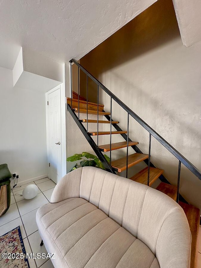 staircase featuring a textured ceiling, baseboards, and tile patterned floors