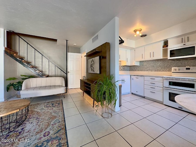 kitchen with light tile patterned floors, white appliances, visible vents, white cabinets, and light countertops