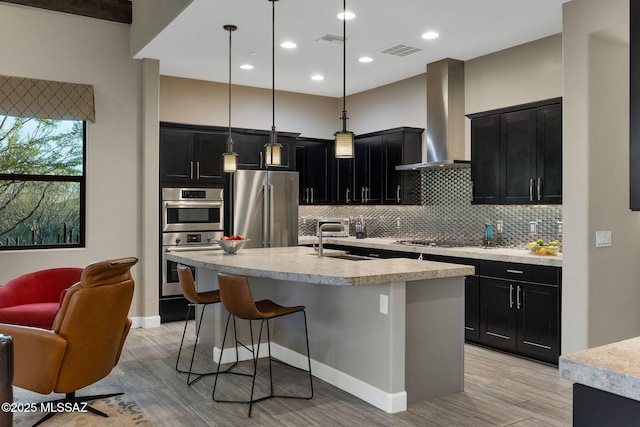 kitchen featuring wall chimney exhaust hood, visible vents, stainless steel appliances, and dark cabinetry