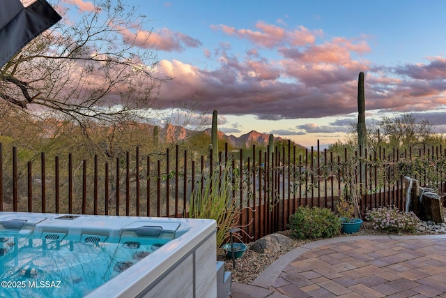 view of patio / terrace with a hot tub and fence