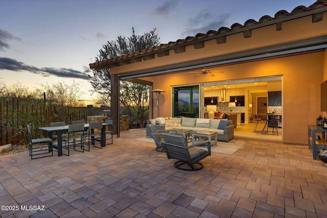 patio terrace at dusk featuring fence, outdoor dining area, and an outdoor living space