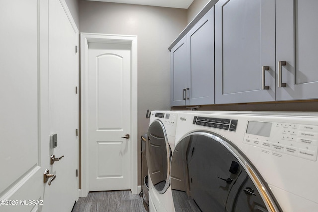 laundry area with separate washer and dryer, light wood-style flooring, and cabinet space