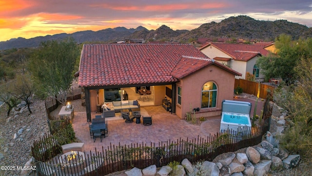 rear view of house featuring a tile roof, stucco siding, outdoor lounge area, a mountain view, and a fenced backyard