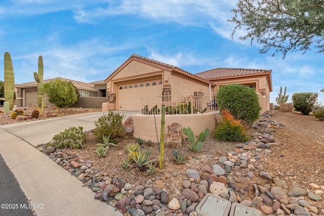 view of front facade featuring stucco siding, fence, a garage, driveway, and a tiled roof