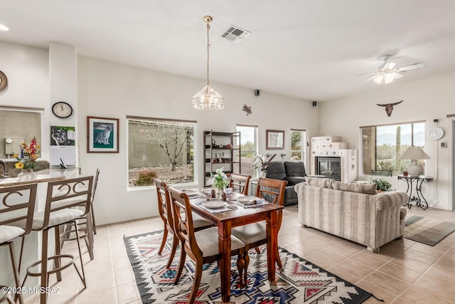 dining space with light tile patterned floors, ceiling fan, a fireplace, and visible vents