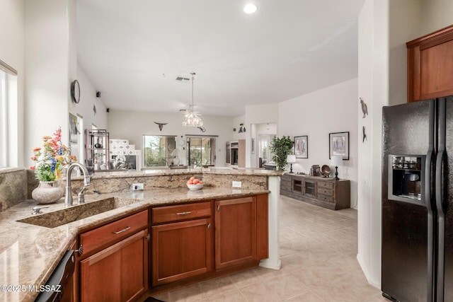 kitchen with open floor plan, brown cabinets, black fridge with ice dispenser, and a sink