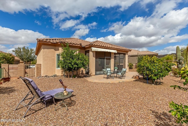 rear view of property with a patio area, a tiled roof, fence, and stucco siding