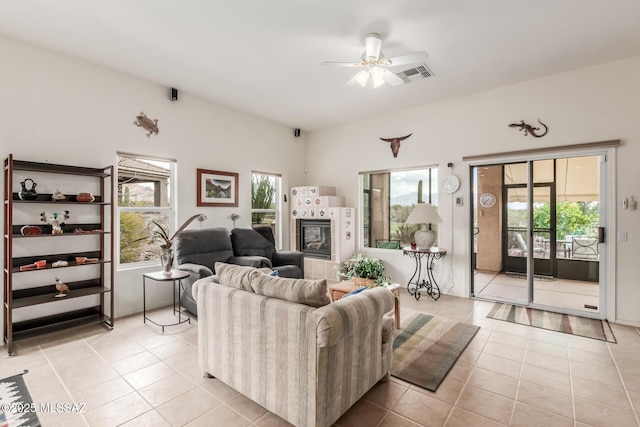 living room with a tile fireplace, visible vents, ceiling fan, and light tile patterned floors