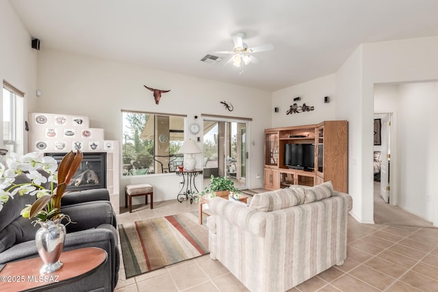 living room featuring a tiled fireplace, visible vents, a wealth of natural light, and light tile patterned flooring