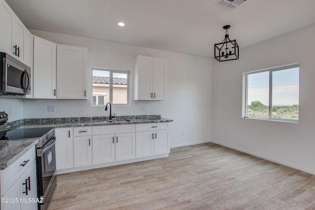 kitchen with stainless steel appliances, stone countertops, a healthy amount of sunlight, and a sink