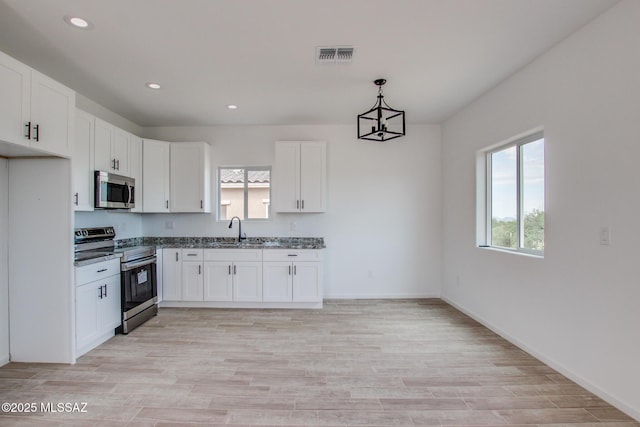 kitchen featuring appliances with stainless steel finishes, a sink, and white cabinets