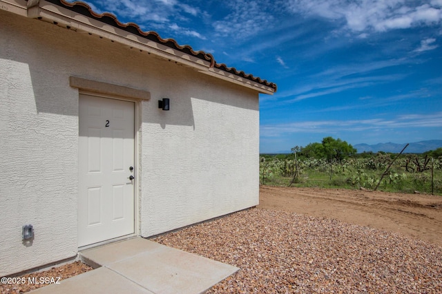 entrance to property with a mountain view, a tiled roof, and stucco siding