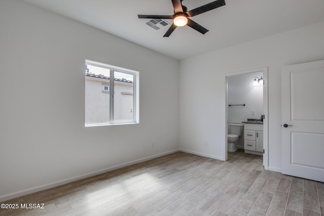 unfurnished bedroom with light wood-style floors, visible vents, baseboards, and ensuite bathroom