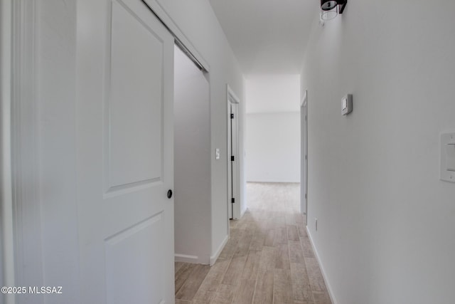 corridor featuring light wood-style floors and baseboards