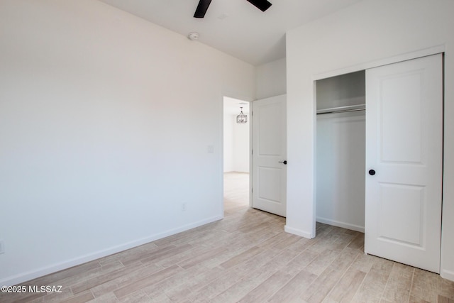 unfurnished bedroom with light wood-type flooring, a ceiling fan, baseboards, and a closet