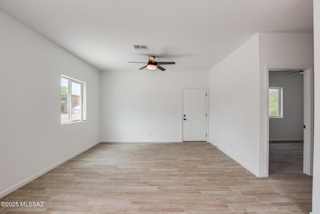 empty room featuring ceiling fan, light wood-style flooring, visible vents, and baseboards