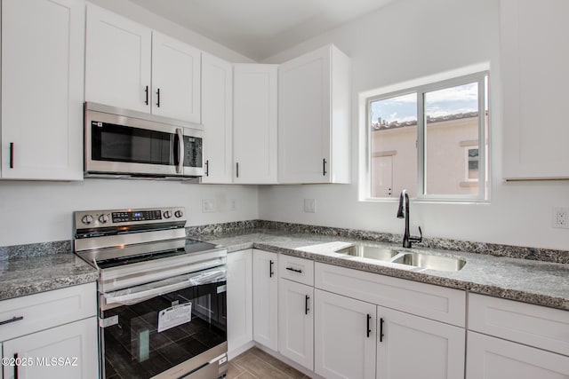 kitchen featuring appliances with stainless steel finishes, white cabinetry, and a sink