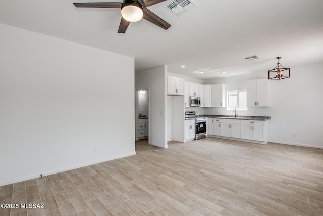 unfurnished living room with light wood finished floors, visible vents, a sink, and recessed lighting