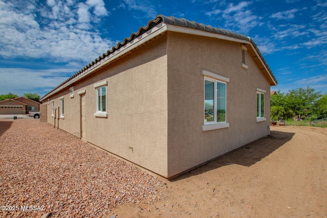 view of home's exterior with a tile roof and stucco siding