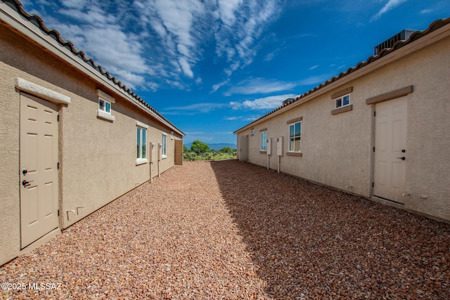 view of property exterior with a tile roof and stucco siding