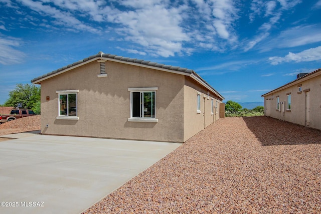 rear view of house with a patio, a tile roof, and stucco siding