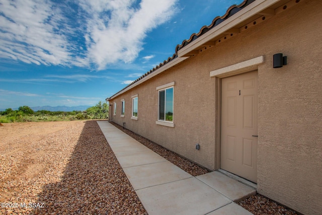 view of side of property featuring a tile roof, a mountain view, and stucco siding