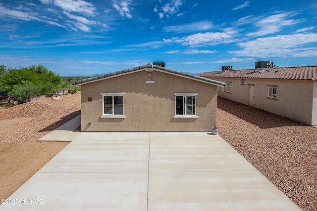 rear view of house featuring central AC, a patio, and stucco siding