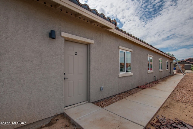 view of property exterior with a tiled roof and stucco siding