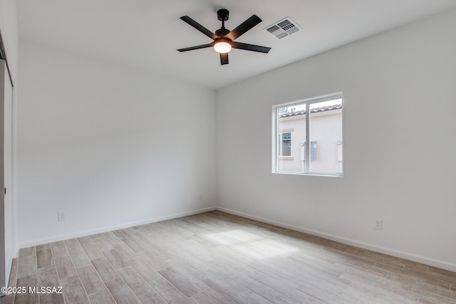 empty room with baseboards, ceiling fan, visible vents, and wood finished floors