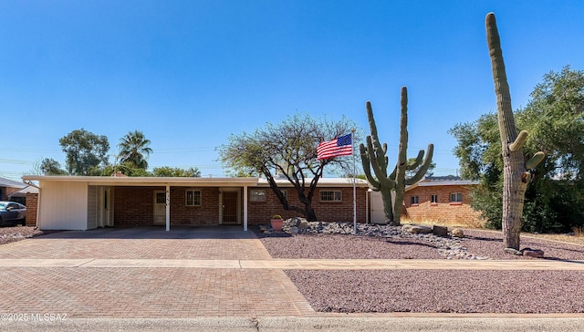 ranch-style home featuring a carport, brick siding, and decorative driveway