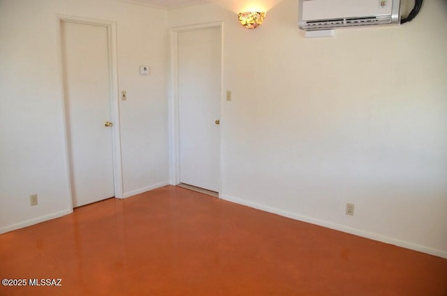 empty room with finished concrete flooring, baseboards, and a wall mounted air conditioner