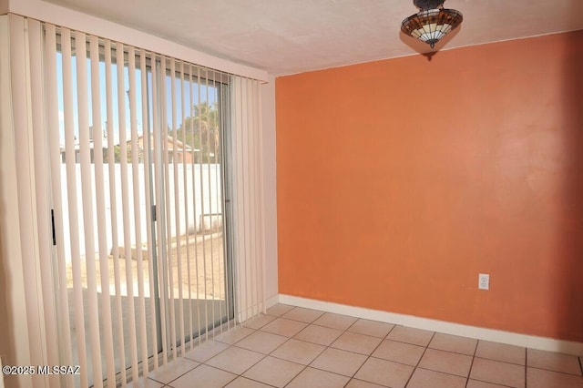 spare room with light tile patterned flooring and baseboards