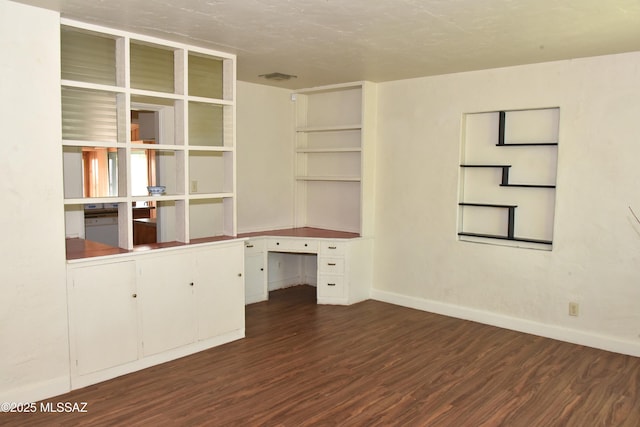 unfurnished office featuring baseboards, visible vents, wood finished floors, and built in study area