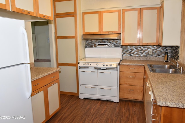 kitchen with white appliances, tasteful backsplash, dark wood-style flooring, under cabinet range hood, and a sink