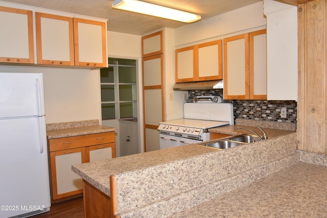 kitchen with tasteful backsplash, light countertops, a sink, white appliances, and under cabinet range hood