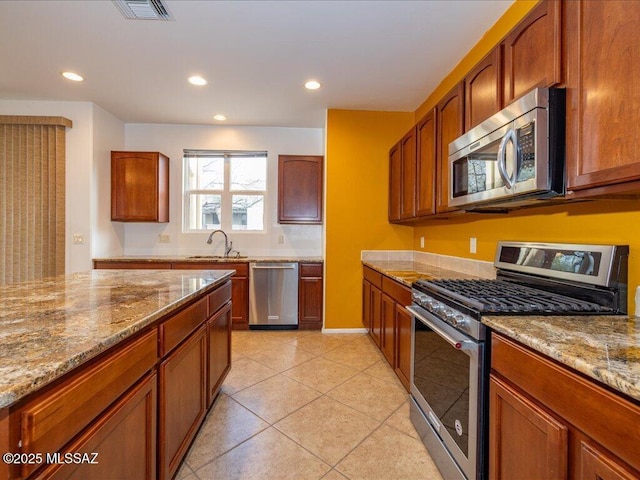 10590 E Maldonado Pl, Tucson, AZ 85747 - kitchen featuring stainless steel appliances, light stone countertops, recessed lighting, light tile patterned floors, and brown cabinets