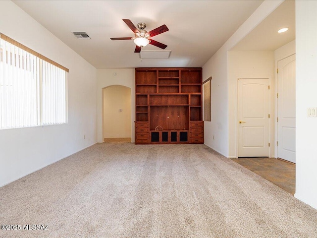 unfurnished living room with arched walkways, ceiling fan, carpet flooring, and visible vents