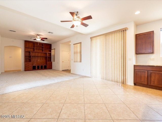 10590 E Maldonado Pl, Tucson, AZ 85747 - unfurnished living room with ceiling fan, built in features, arched walkways, light tile patterned floors, and recessed lighting