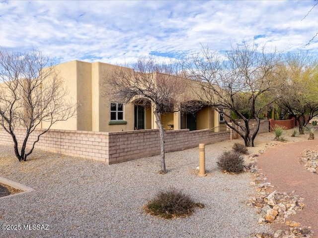 adobe home with a fenced front yard and stucco siding