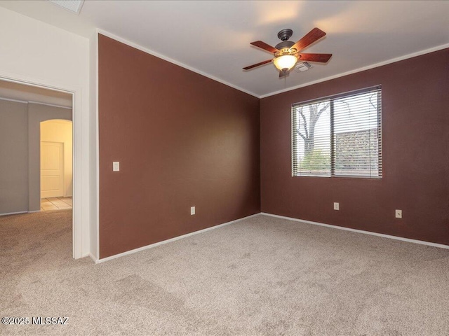 spare room with ornamental molding, carpet, arched walkways, and a ceiling fan