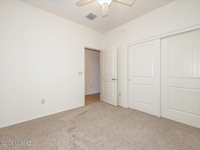 unfurnished bedroom featuring ceiling fan, a closet, visible vents, and carpet flooring