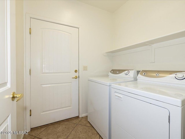 clothes washing area with laundry area, washer and clothes dryer, and light tile patterned flooring