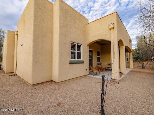 exterior space with a patio, fence, and stucco siding