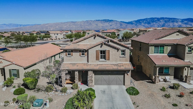 view of front of home featuring concrete driveway, a mountain view, a residential view, stone siding, and a tiled roof