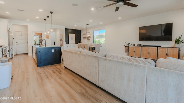 living area with ceiling fan with notable chandelier, light wood finished floors, visible vents, and recessed lighting