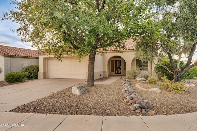 view of front of house with a garage, a tiled roof, concrete driveway, and stucco siding