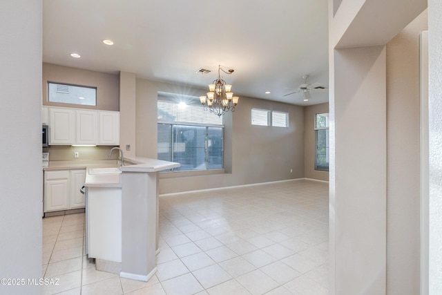 kitchen with light tile patterned floors, a peninsula, light countertops, white cabinetry, and a sink