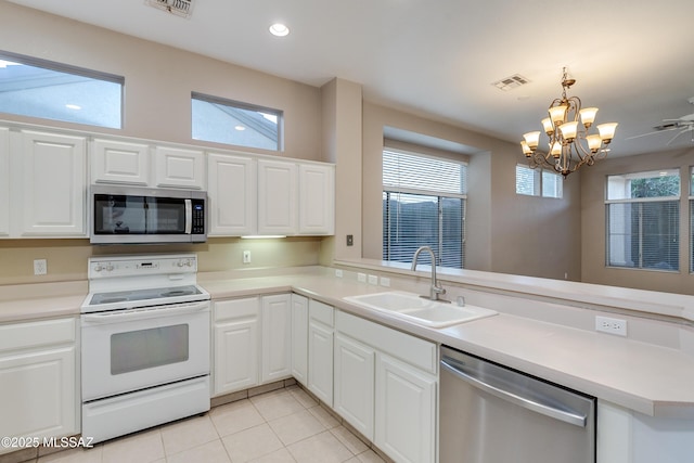 kitchen featuring stainless steel appliances, visible vents, white cabinets, a sink, and a peninsula